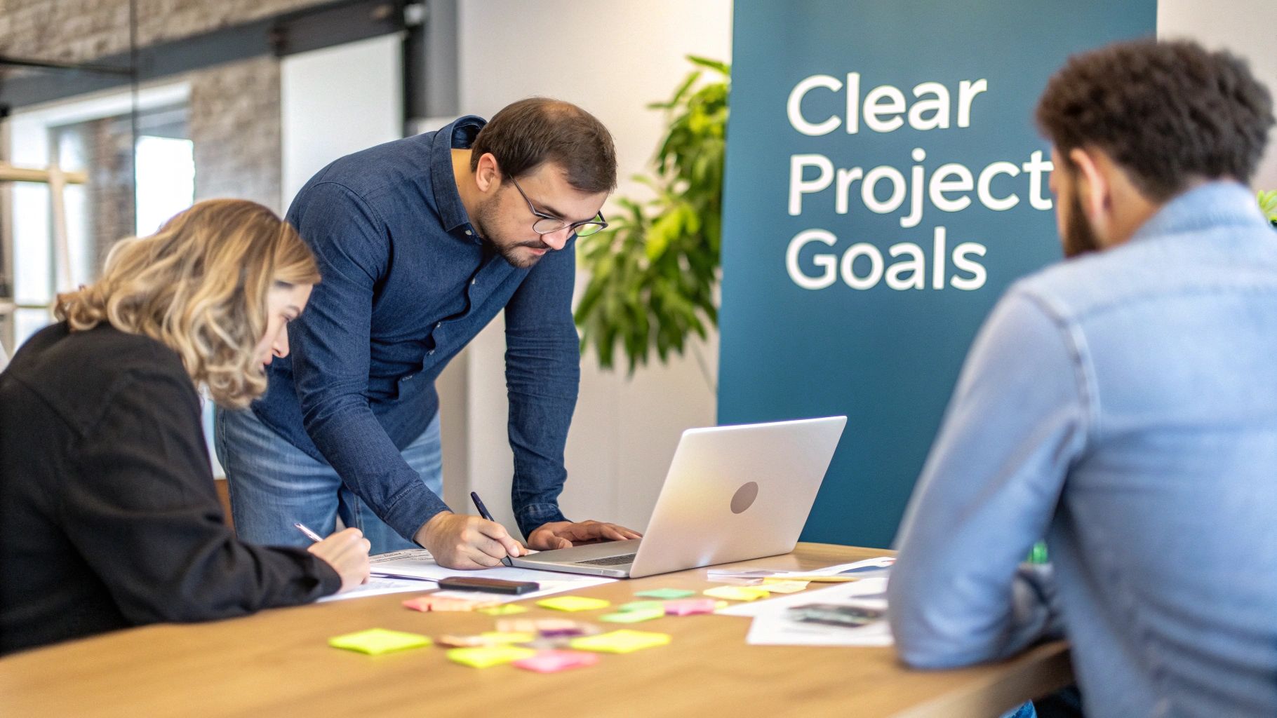 Three colleagues collaborate on a software project, brainstorming ideas with a laptop and sticky notes.